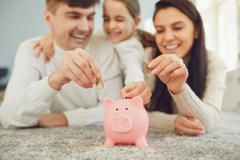 Parents and girl putting coins into a piggy bank