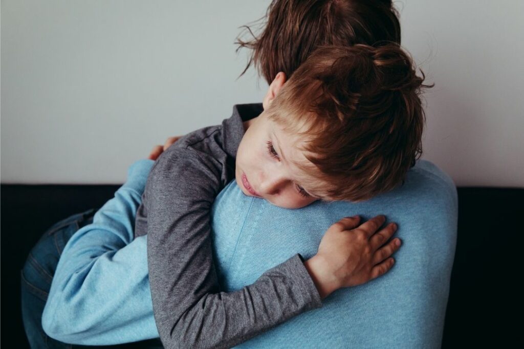 Young boy who is sad hugging his mother